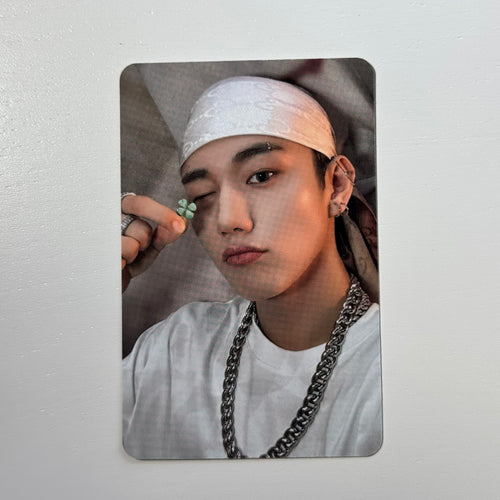Portrait photocard of a man in a light pink cap and white shirt with chain necklace