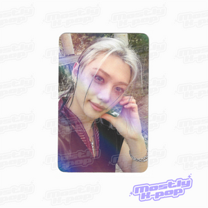 Rounded photo card of an idol portrait with light hair, hand resting near jaw