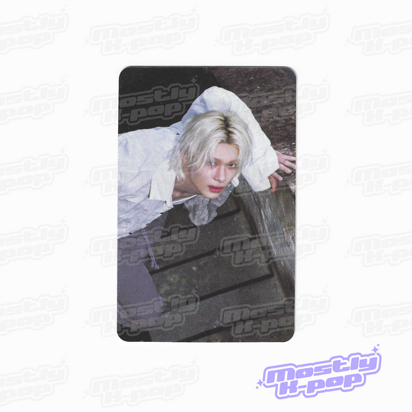 Rectangular photo card featuring a person with light hair wearing a white hooded top.