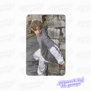 Rectangular photo card featuring a person in a gray top and white pants, standing outdoors.