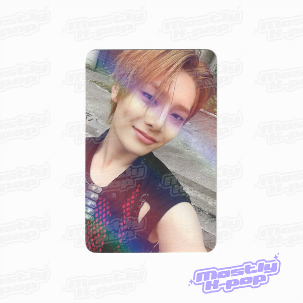 Round-corner photo card of a member with light brown hair, sideways smile, iridescent print