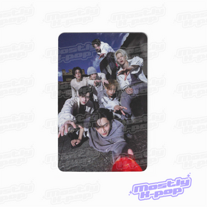 Rectangular photo card showing a group of people outdoors posing together, wearing light outfits.