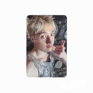 Portrait photo card of a man with blond hair, wearing a silver sleeveless top and making a thumbs-up.