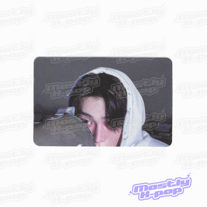Rectangular photo card featuring a person in a light hood and dark outfit, close-up.